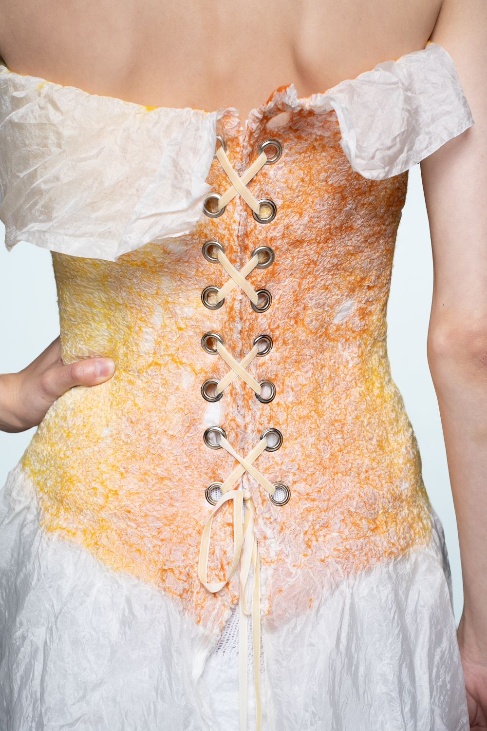 The corset is made from hand-felted fabric that combines 100% merino wool and 100% silk.The adjustable ribbon fastening at the back allows you to customise the fit. The corset features supportive boning and a 100% cotton lining.The white centre gradually transitions into increasingly intense colour, with the sides reaching a beautiful depth of colour. This seamless gradient creates a playful and harmonious design.Every Kristina Oja corset is a unique work of art. Subtle variations in colour and texture resulting from the hand-dyeing and felting processes are part of its beauty, making each piece truly one of a kind.